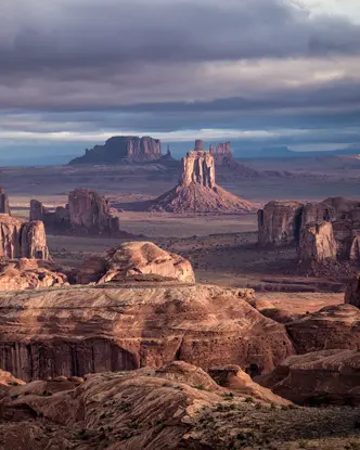 Vast desert landscape with remarkable rock formations under a cloudy sky.