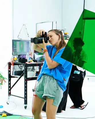 Photographer takes a picture in a studio of a model in a green net outfit.