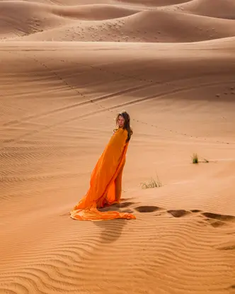 Woman in an orange dress standing in the desert.