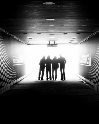 Four people are standing in a stadium tunnel with the sign "Stade France" in the light at the end of the corridor.