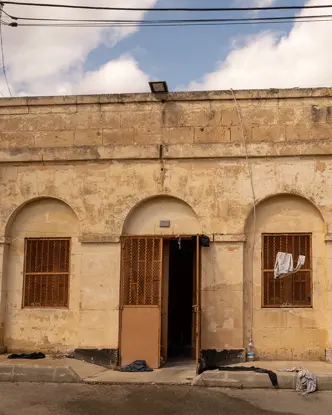 Older stone building with barred windows and clothes hanging outside.