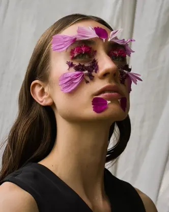 Ein Portrait einer Frau mit Blumen auf ihrem Gesicht.