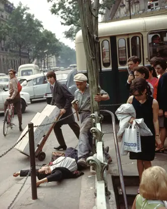 A young man in a suit and tie lies on his back with arms stretched above his head, directly next to the metro station