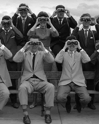 Women and men in 1960 with binoculars in front of their faces