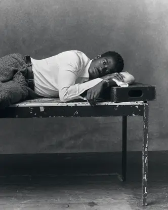 Portrait en noir et blanc de l'acteur Damson Idris allongé sur une table