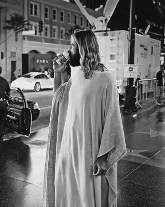 man in a jesus cosplay eating icecream b&w