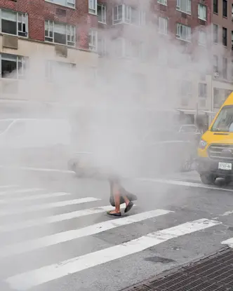 A woman walks along a pavement through the fog