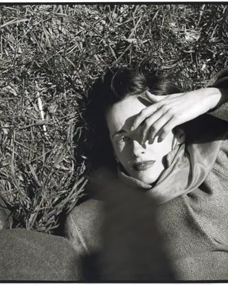 Frau liegt im im Gras und hält sich Hand ins Gesicht, Saul Leiter