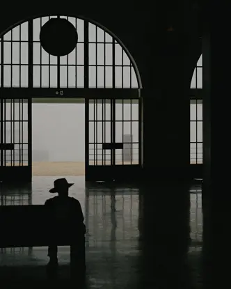 Ombre d'un homme assis dans une gare avec un chapeau