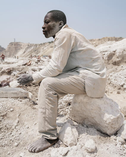 A man sitting on a small rock. 