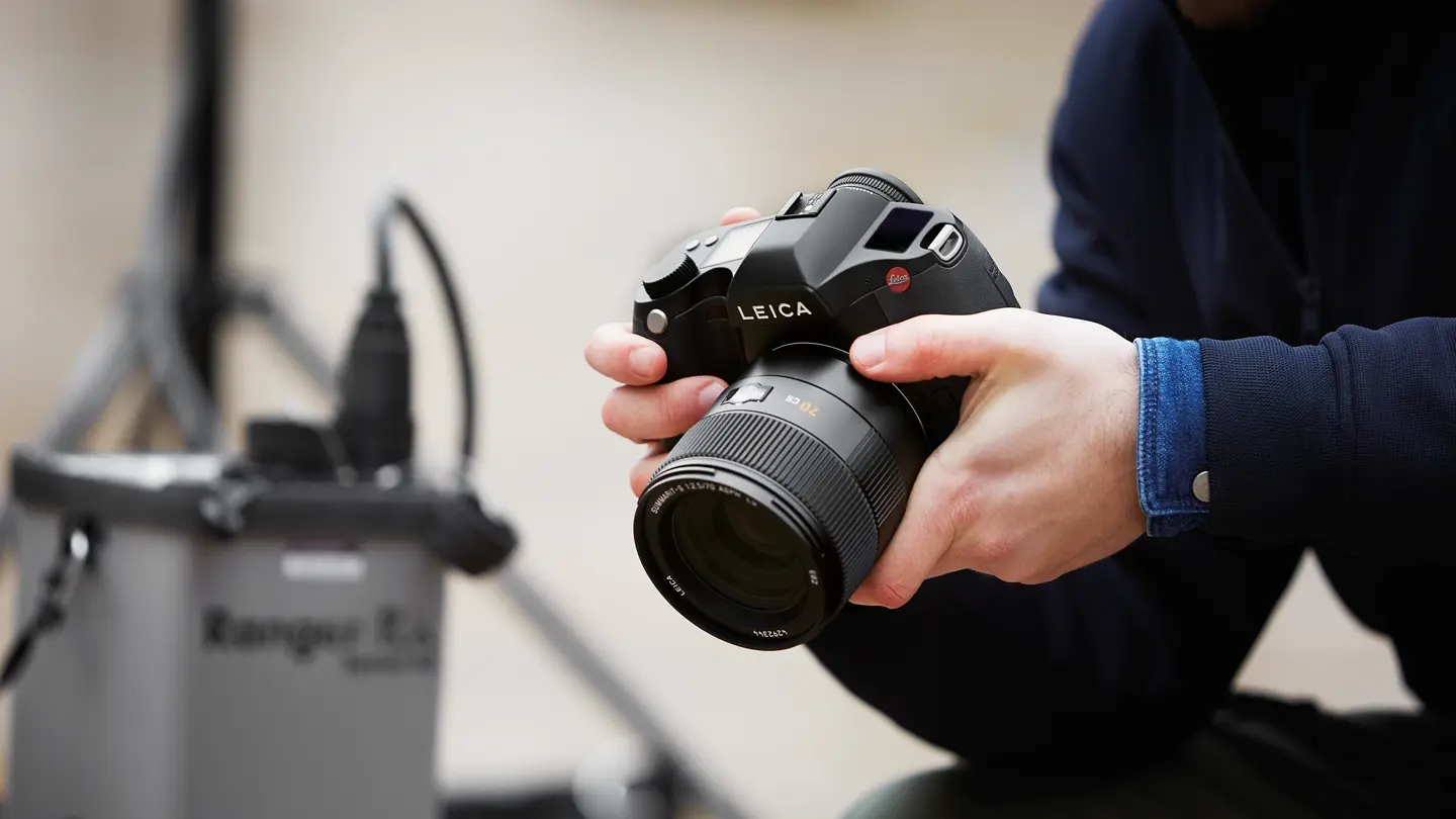 Close-up of a man holding a Leica camera in his hands