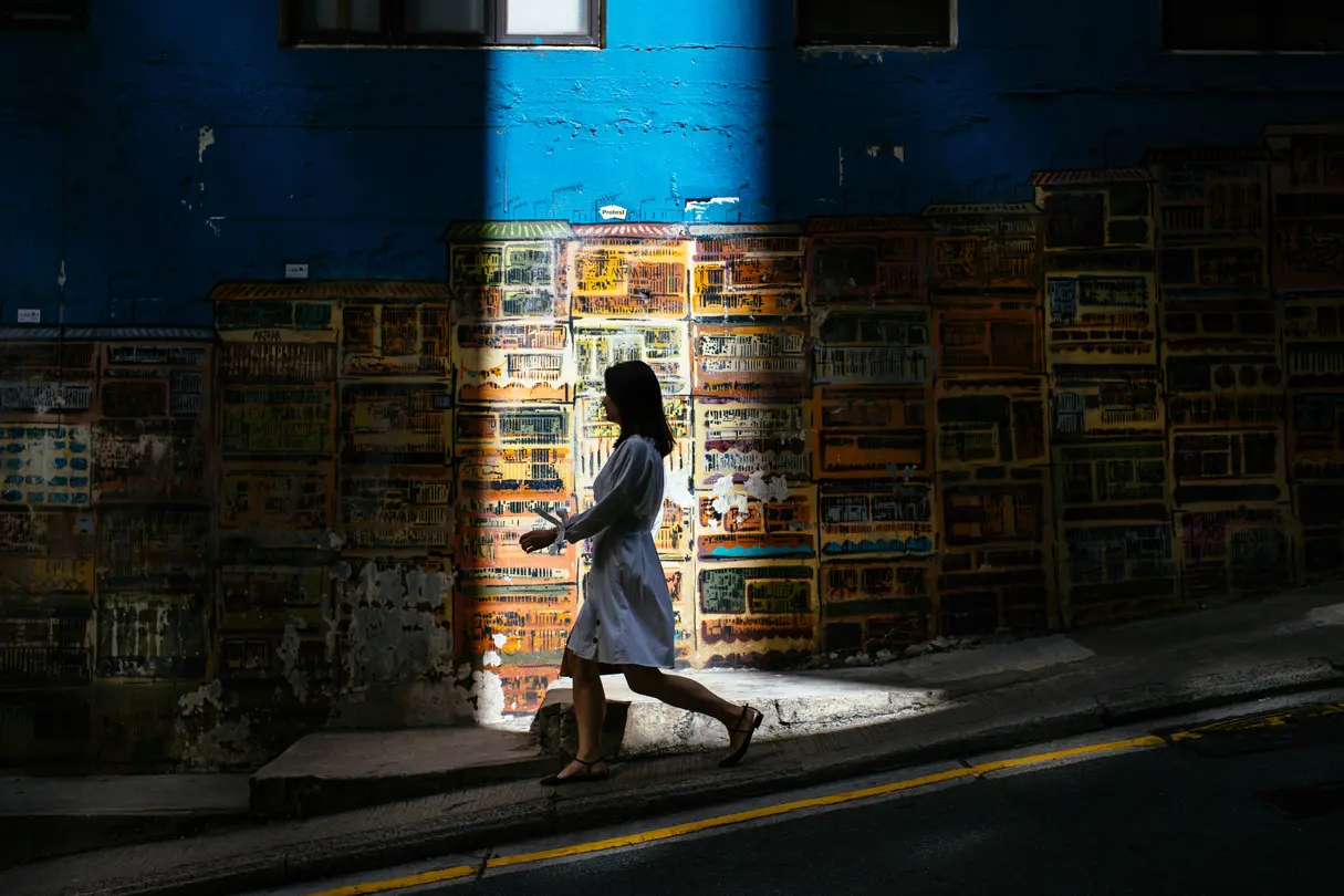 Woman walking down a road with sun shining on her